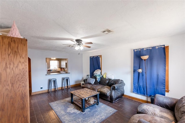 living room featuring ceiling fan and a textured ceiling