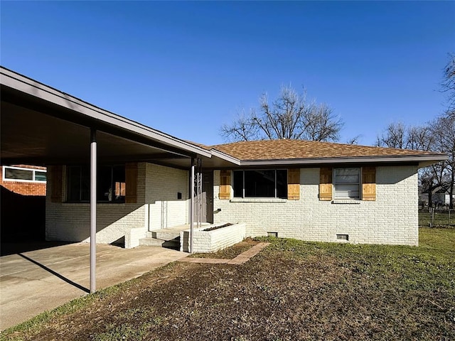 view of side of property with crawl space, brick siding, and roof with shingles