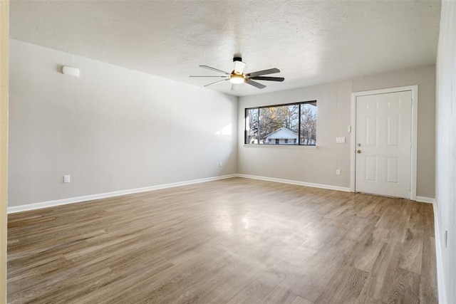 unfurnished room featuring a textured ceiling, baseboards, ceiling fan, and wood finished floors