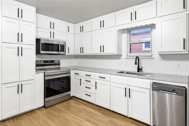 kitchen featuring light wood-style flooring, white cabinets, appliances with stainless steel finishes, and a sink