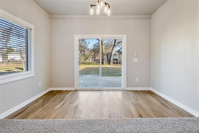 unfurnished dining area featuring a notable chandelier, wood finished floors, and baseboards