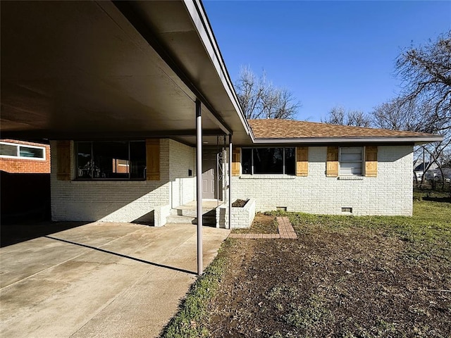 exterior space featuring crawl space, brick siding, and roof with shingles