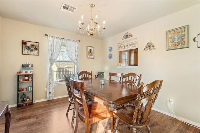 dining space with dark wood-type flooring and an inviting chandelier