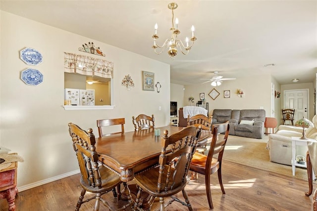 dining room with ceiling fan with notable chandelier and wood-type flooring