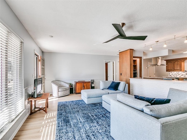 living room with ceiling fan, track lighting, a textured ceiling, and light hardwood / wood-style floors