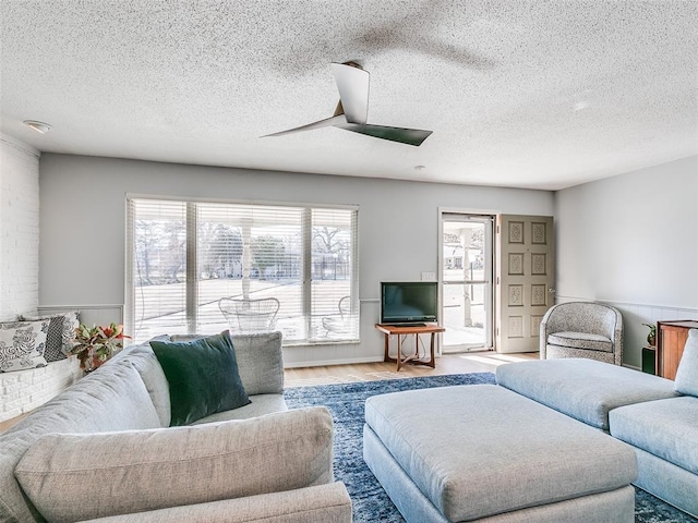 living room with ceiling fan, light hardwood / wood-style flooring, and a textured ceiling