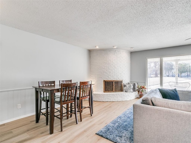 dining area with a textured ceiling, light hardwood / wood-style floors, and a fireplace