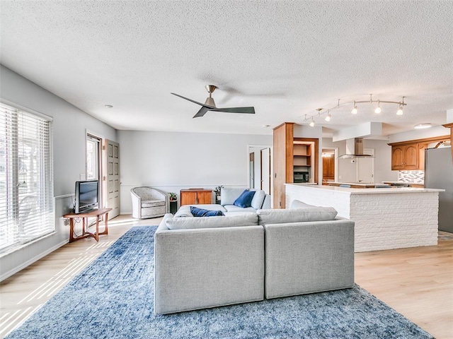 living room featuring a textured ceiling, light hardwood / wood-style floors, and ceiling fan