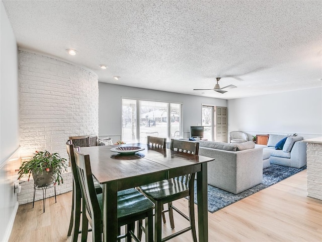 dining space with ceiling fan, hardwood / wood-style flooring, and a textured ceiling