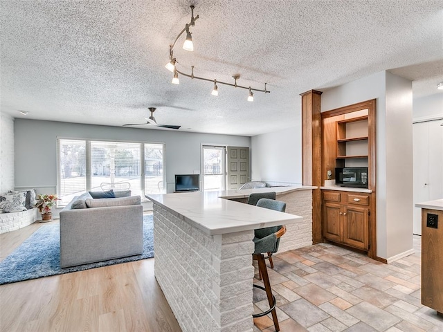 kitchen with rail lighting, a breakfast bar, and ceiling fan