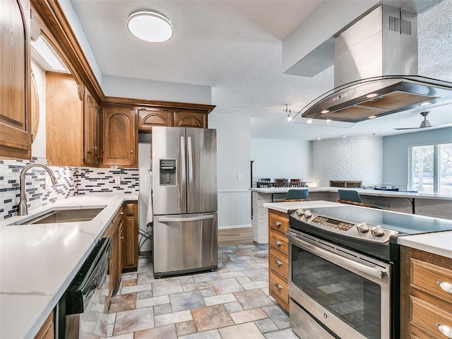 kitchen with appliances with stainless steel finishes, sink, backsplash, island exhaust hood, and a textured ceiling