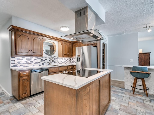 kitchen with appliances with stainless steel finishes, island range hood, sink, decorative backsplash, and a center island