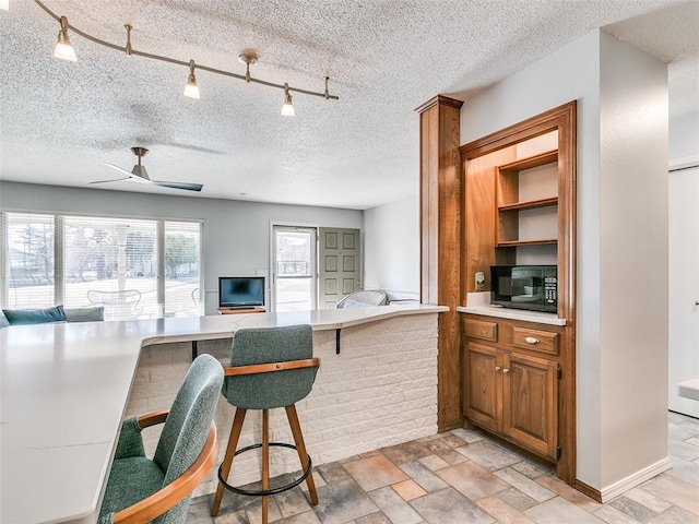 kitchen featuring a breakfast bar area, track lighting, a textured ceiling, and kitchen peninsula