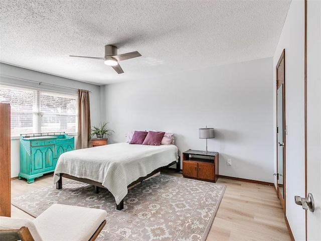 bedroom featuring light wood-type flooring, a textured ceiling, and ceiling fan