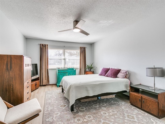 bedroom with a textured ceiling, light hardwood / wood-style floors, and ceiling fan