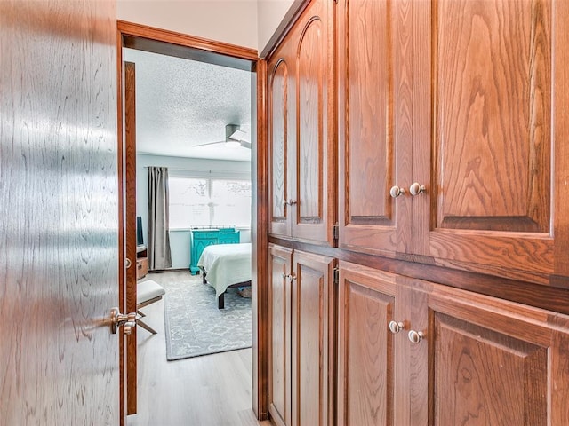 corridor with a textured ceiling and light wood-type flooring