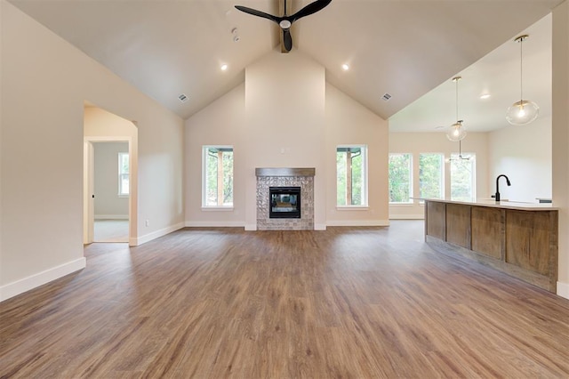 unfurnished living room with ceiling fan, high vaulted ceiling, a high end fireplace, and hardwood / wood-style floors