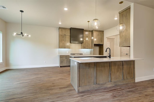kitchen featuring pendant lighting, wall chimney exhaust hood, dark hardwood / wood-style flooring, tasteful backsplash, and sink