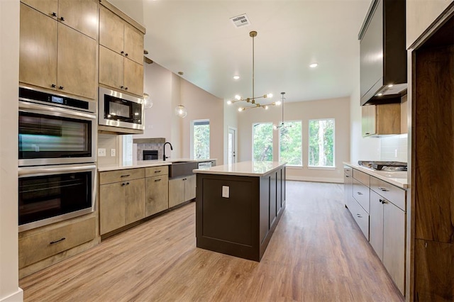kitchen with a center island, light hardwood / wood-style floors, vaulted ceiling, pendant lighting, and stainless steel appliances