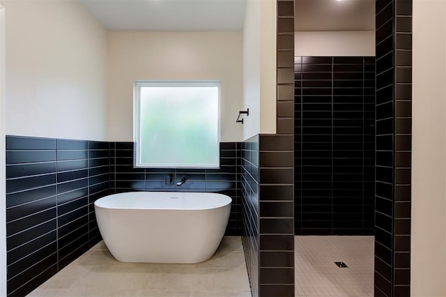bathroom with tile patterned floors, shower with separate bathtub, and tile walls