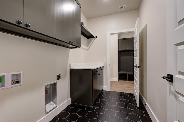 laundry area with washer hookup, electric dryer hookup, dark tile patterned floors, and cabinets