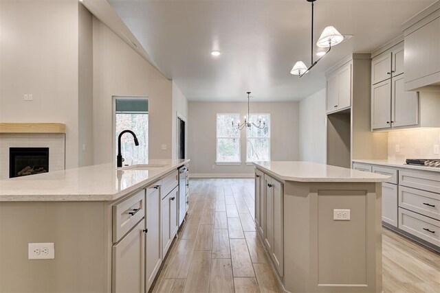 kitchen featuring pendant lighting, sink, light hardwood / wood-style flooring, and a center island with sink