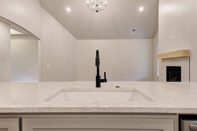 interior space featuring a brick fireplace, sink, and a chandelier