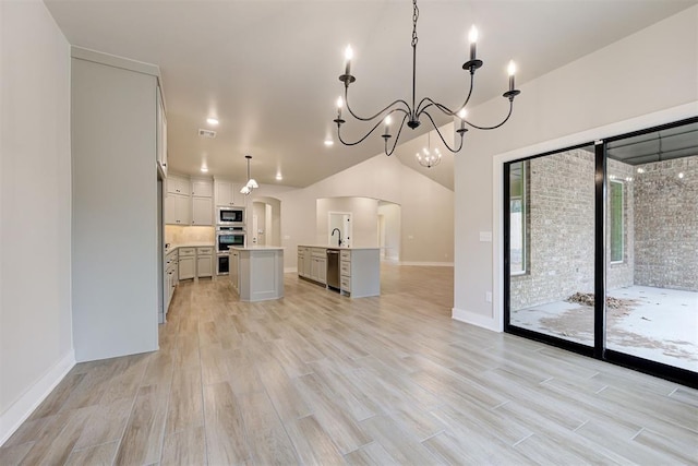 kitchen with sink, decorative light fixtures, a center island with sink, light hardwood / wood-style flooring, and stainless steel appliances