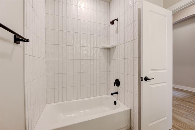 bathroom with hardwood / wood-style flooring and tiled shower / bath