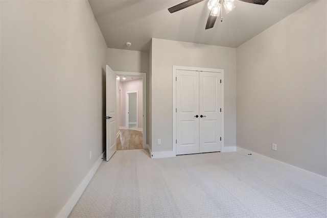 unfurnished bedroom featuring light carpet, ceiling fan, and a closet