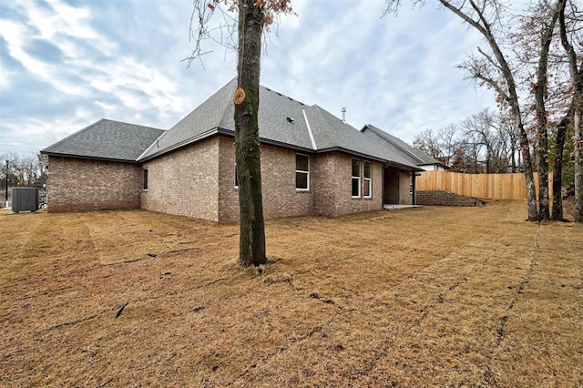 back of house with central AC unit and a yard