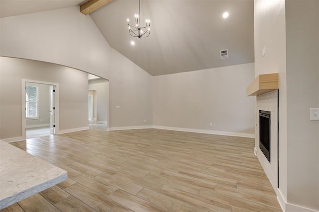 unfurnished living room featuring beamed ceiling, high vaulted ceiling, a chandelier, and light wood-type flooring