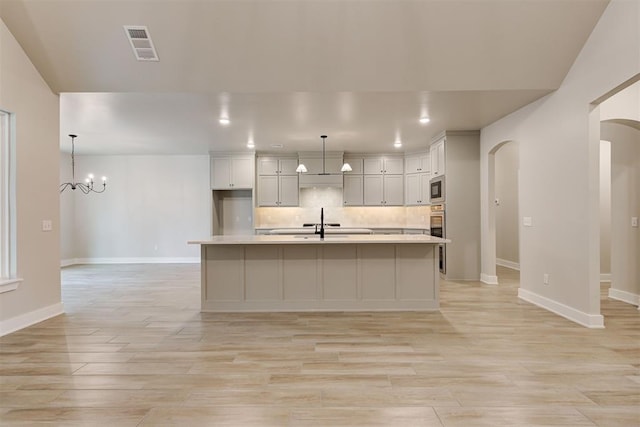 kitchen featuring pendant lighting, an island with sink, and decorative backsplash