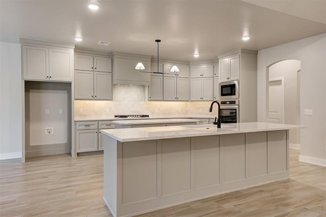 kitchen featuring built in microwave, a kitchen island with sink, and oven