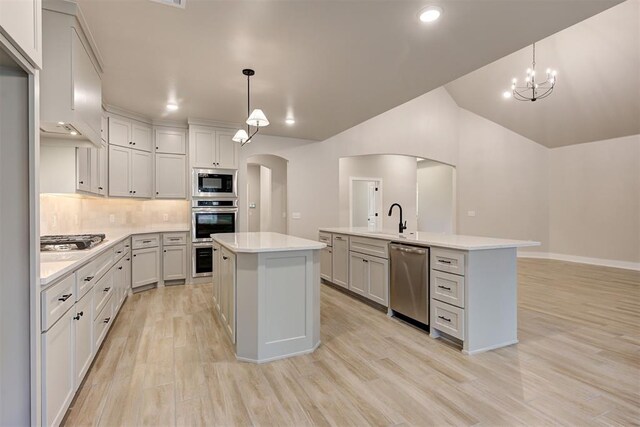 kitchen featuring decorative light fixtures, stainless steel appliances, and a center island with sink