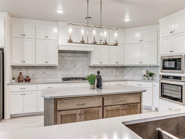 kitchen with decorative light fixtures, tasteful backsplash, white cabinetry, and stainless steel appliances