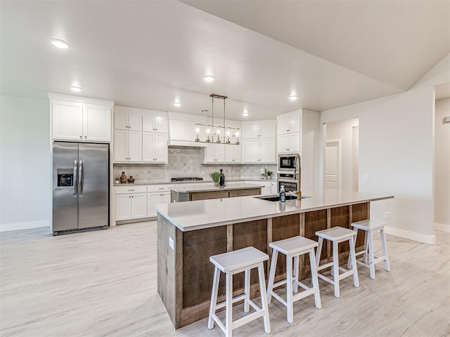 kitchen with black microwave, decorative light fixtures, stainless steel refrigerator with ice dispenser, and a spacious island