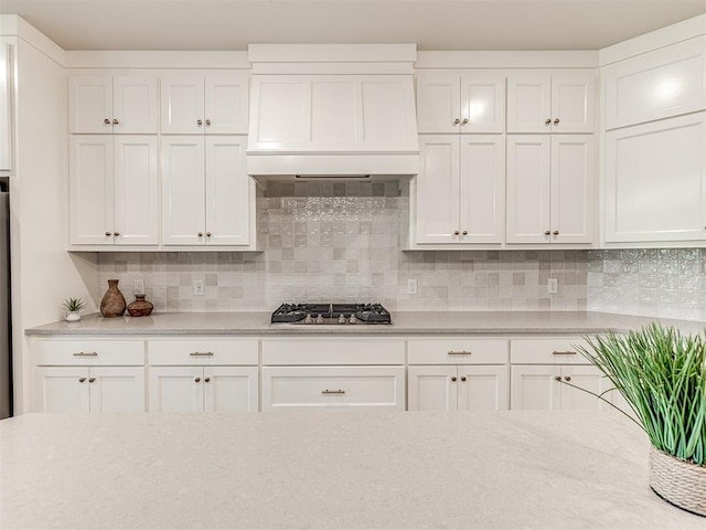 kitchen featuring backsplash, white cabinetry, custom range hood, and stainless steel gas cooktop