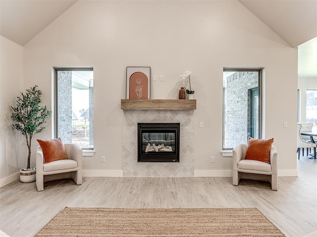 sitting room with a tiled fireplace, hardwood / wood-style floors, and lofted ceiling