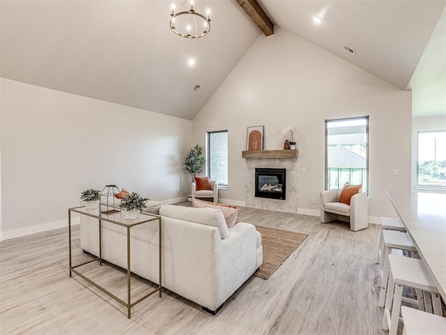 living room with light wood-type flooring, a fireplace, high vaulted ceiling, a notable chandelier, and beamed ceiling