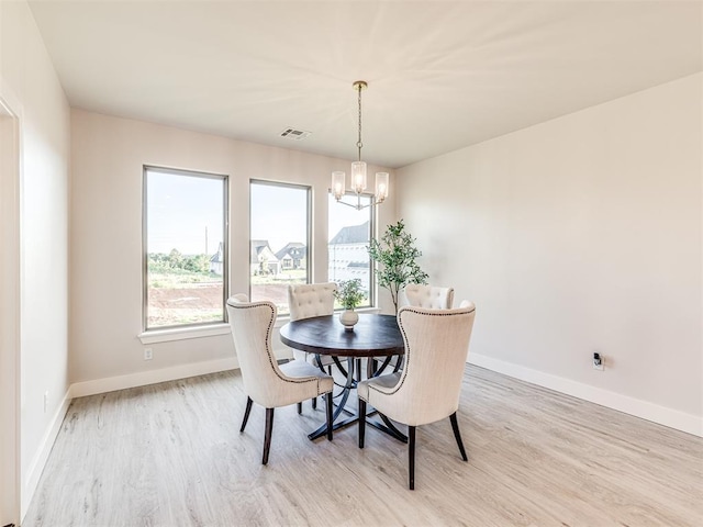 dining room with light hardwood / wood-style floors and an inviting chandelier