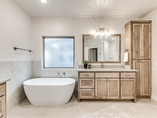 bathroom featuring tile patterned floors, tile walls, a bathtub, and vanity