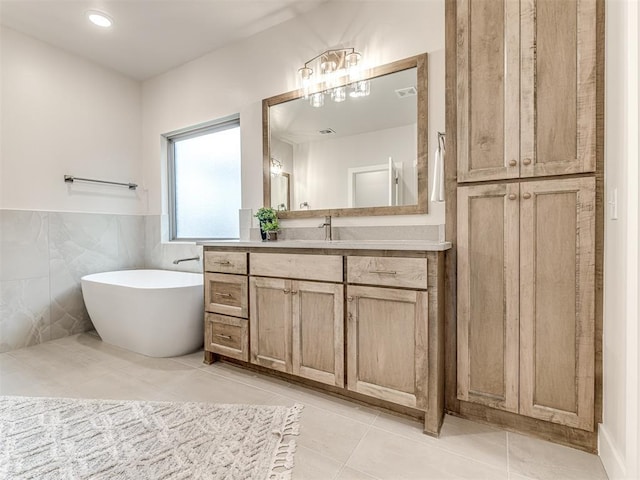 bathroom featuring vanity, a bathing tub, tile walls, and tile patterned flooring