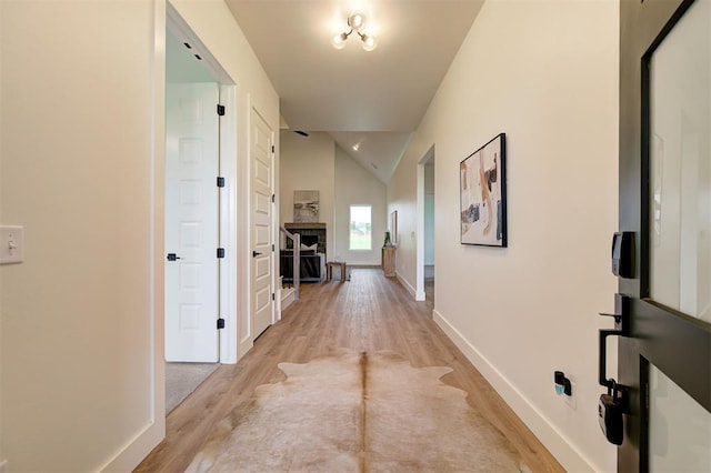 hallway with vaulted ceiling and light hardwood / wood-style floors