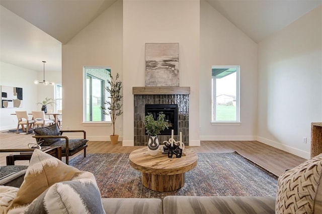 living room featuring high vaulted ceiling, a tiled fireplace, and plenty of natural light