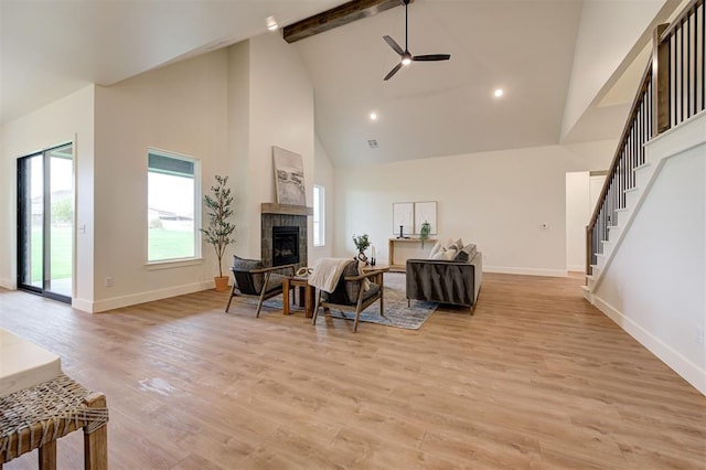 living room with beam ceiling, high vaulted ceiling, a fireplace, and light hardwood / wood-style floors