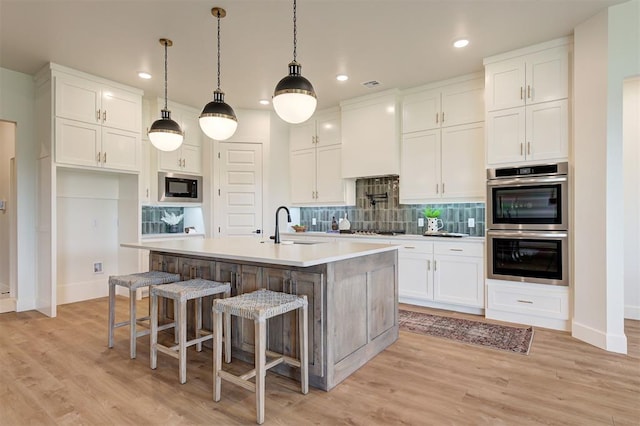 kitchen featuring stainless steel appliances, white cabinets, and a kitchen island with sink