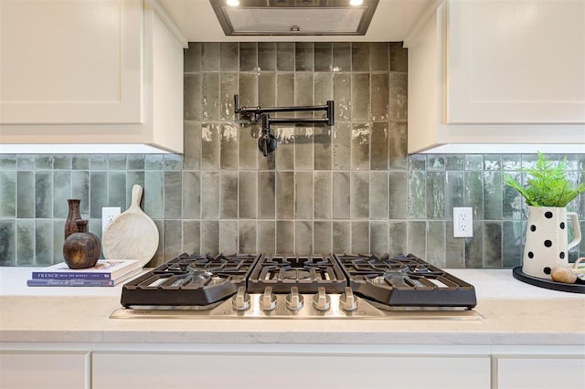 kitchen with white cabinets, decorative backsplash, light stone countertops, and stainless steel gas cooktop