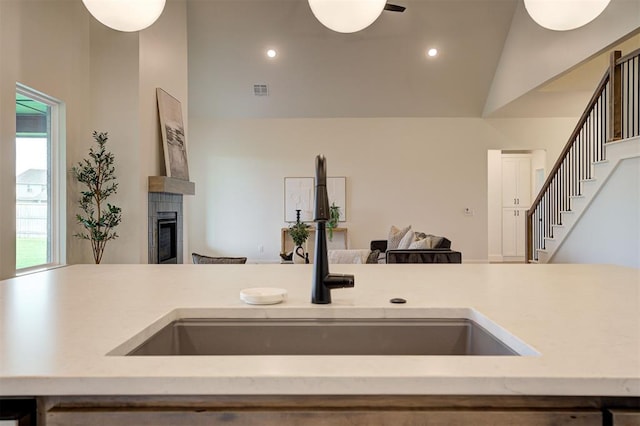 kitchen featuring vaulted ceiling, a tile fireplace, and sink