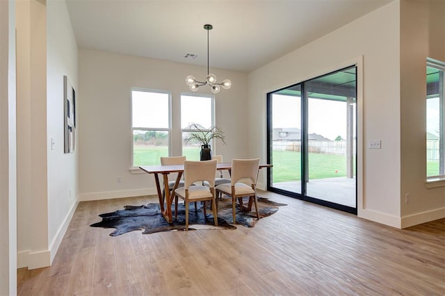 dining space with light hardwood / wood-style floors and an inviting chandelier